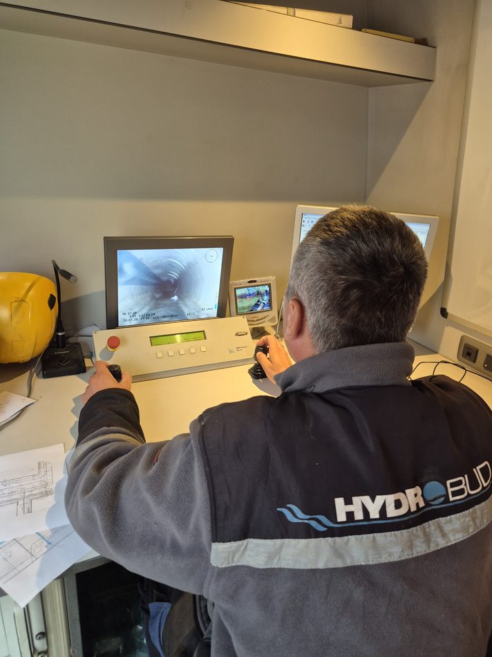 Operator HYDROBUD przy pulpicie kamerowozu — na monitorze podgląd z kamery wewnątrz rurociągu